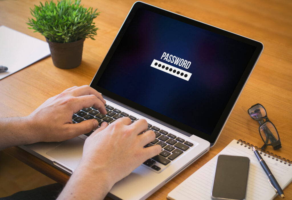 ノートパソコンのキーボードに置かれた手と画面に表示されたパスワードの文字