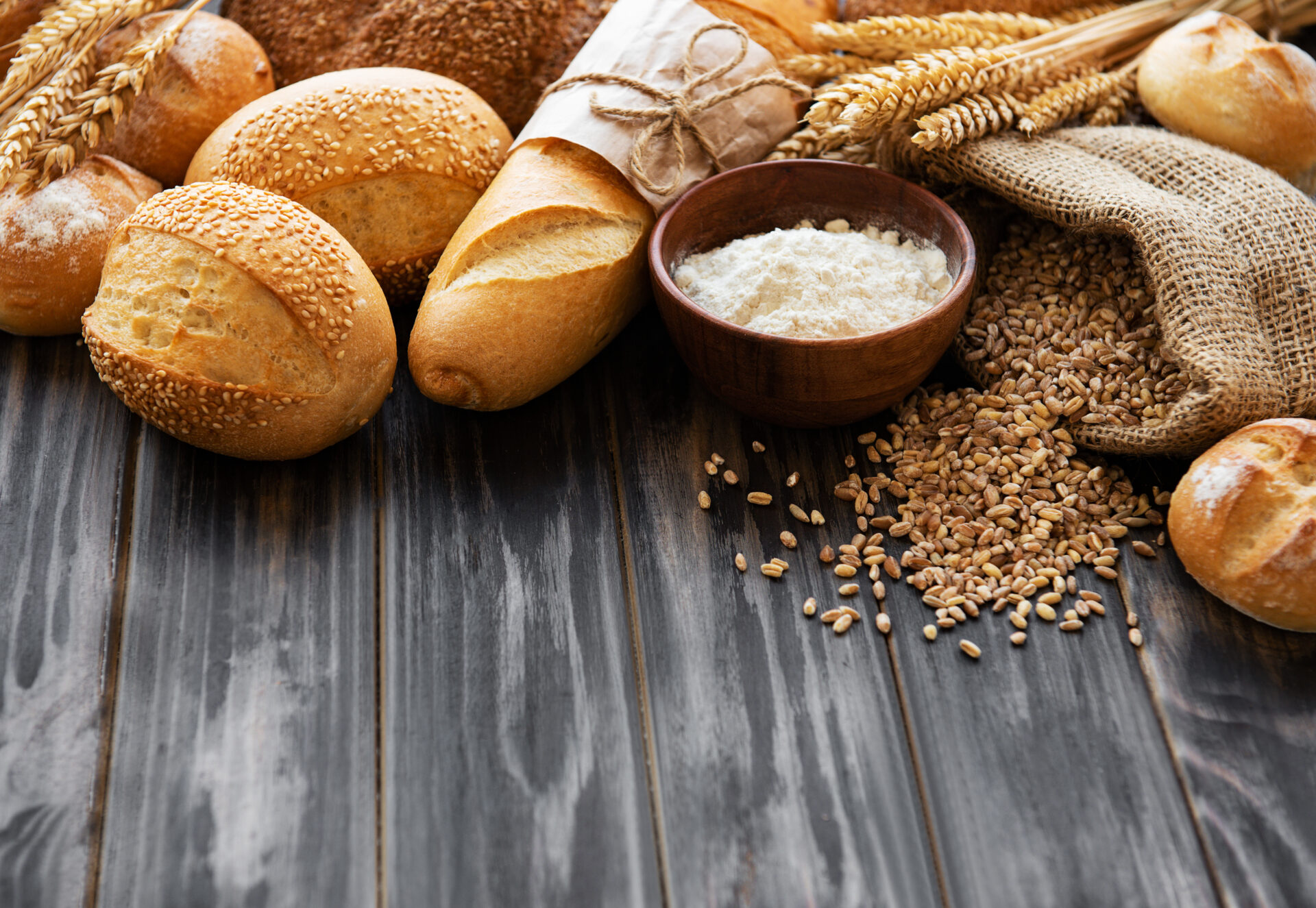 板の上に並ぶバラエティ豊かなパンと小麦