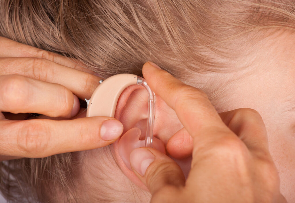 耳に補聴器を付けようとしている手元と耳のアップ