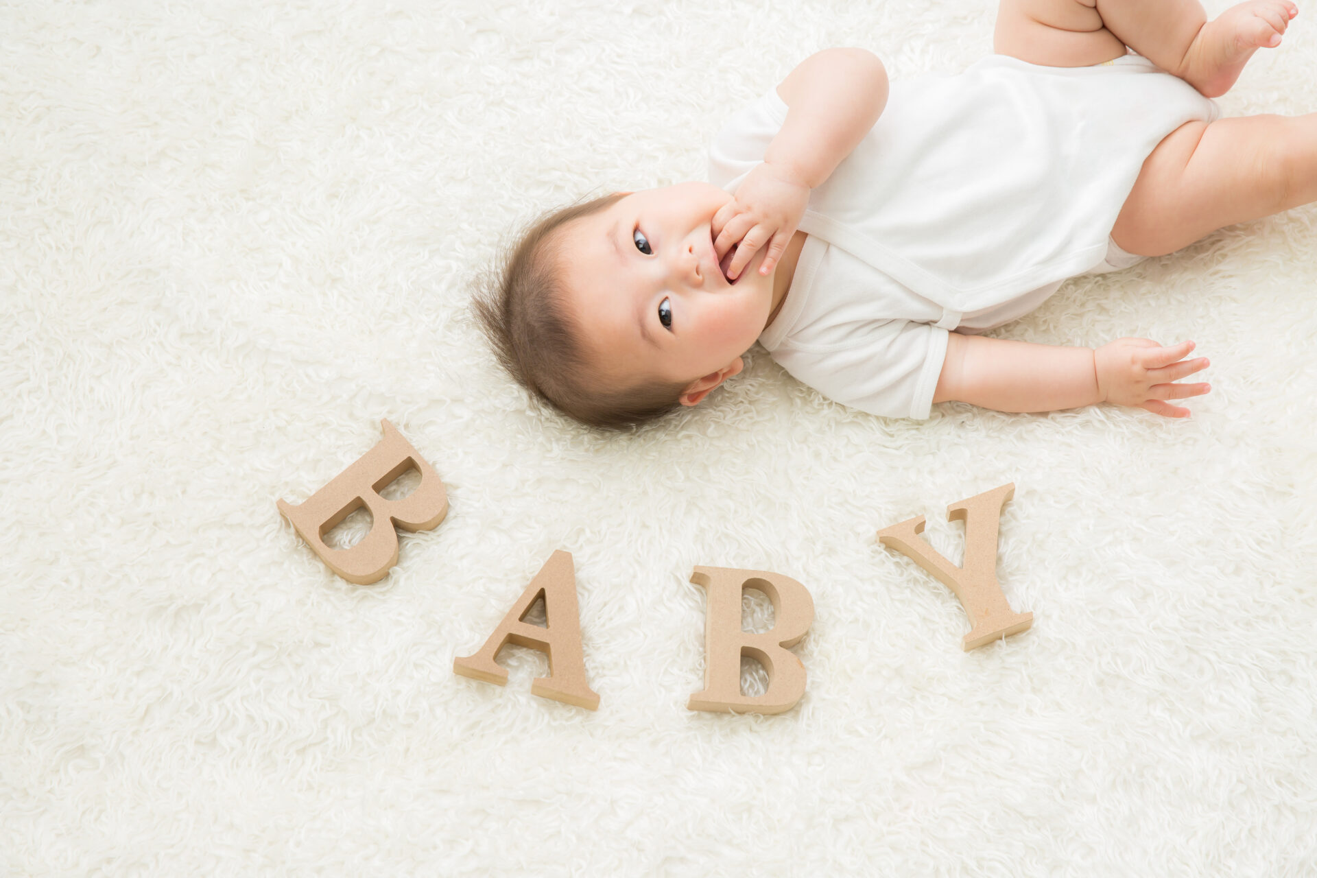 横たわった赤ちゃんと横にBABYのロゴ文字