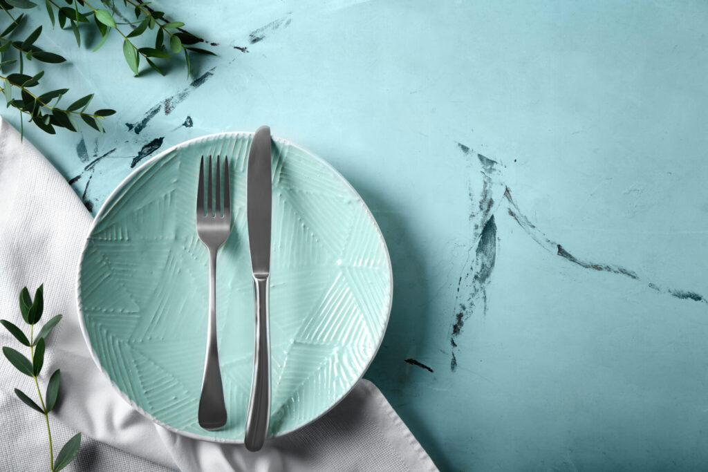 青いテーブルに置かれたお皿とフォークナイフ