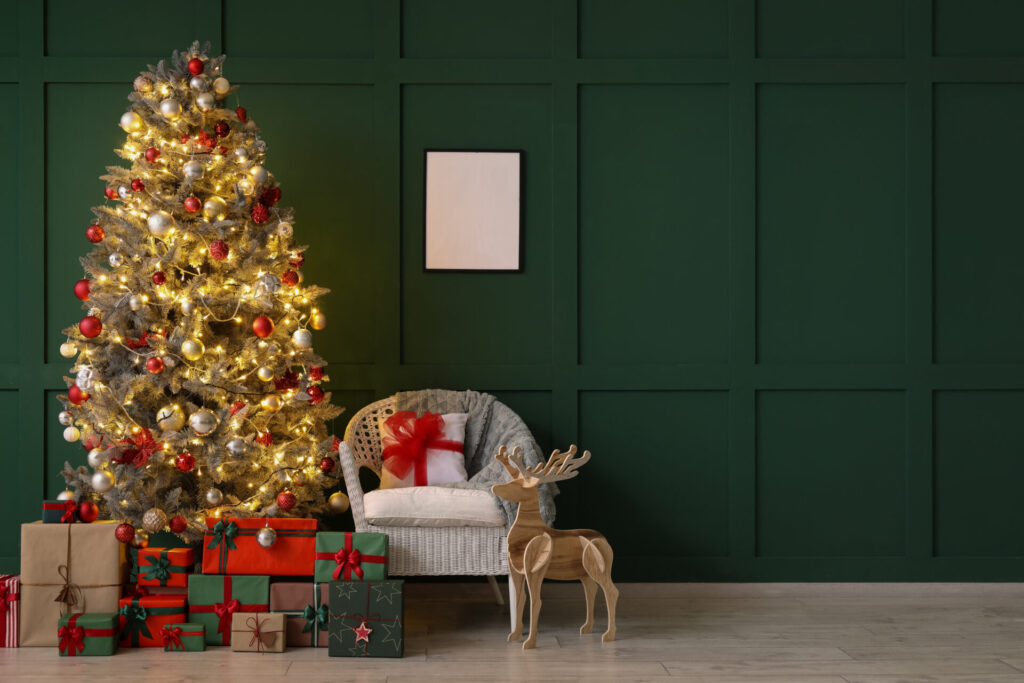 緑の壁をバッグに飾られたクリスマスツリーとたくさんのプレゼントやトナカイのオブジェ