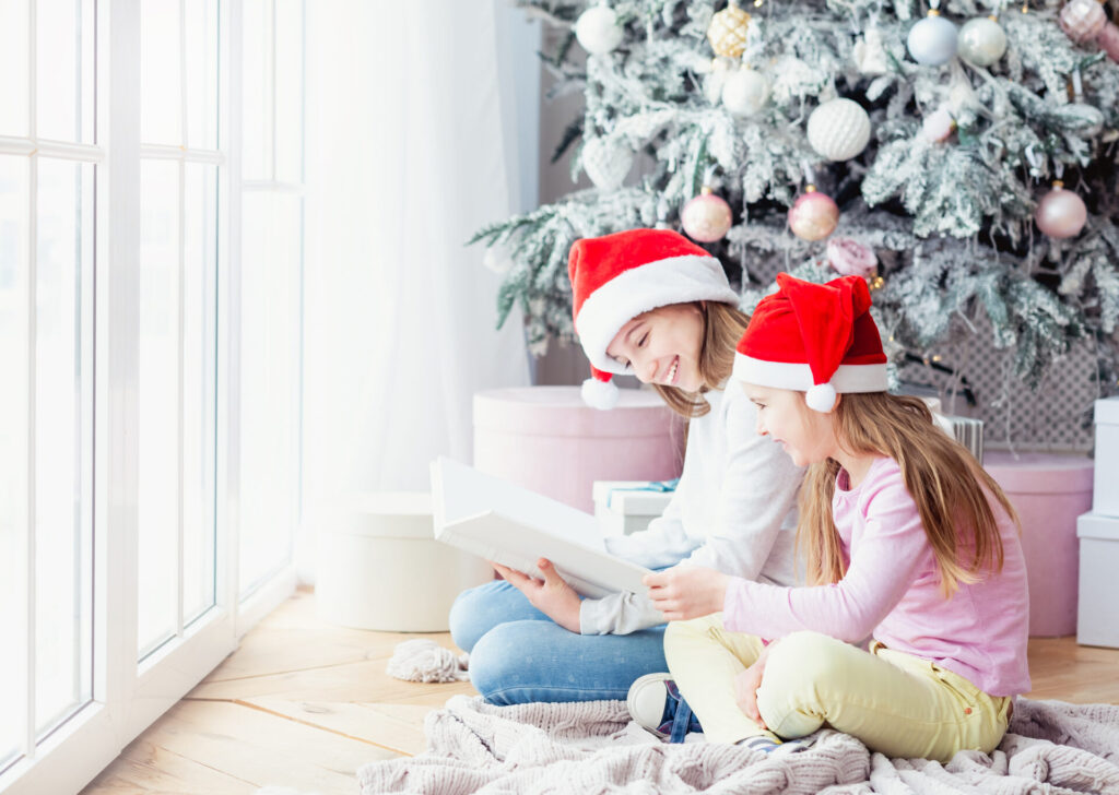 クリスマスツリーの前でサンタ帽子をかぶり微笑む子供の姉妹