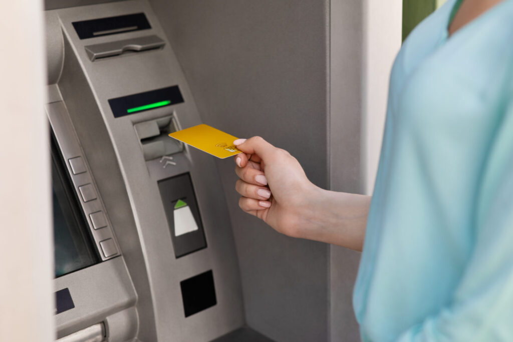 ATMにカードを入れる女性の手元