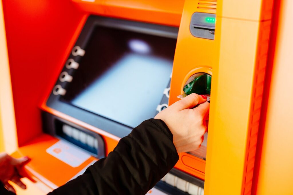ATMにカードを挿入する女性の手元