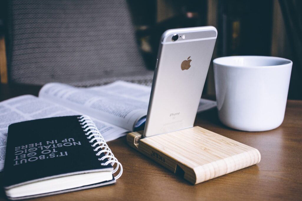 机の上に置かれたiPhoneとノートとコーヒー
