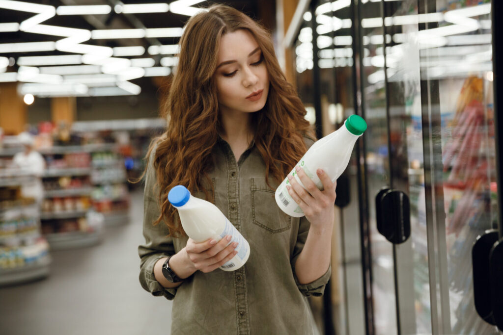 スーパーでミルクを選んでいる髪の長い女性