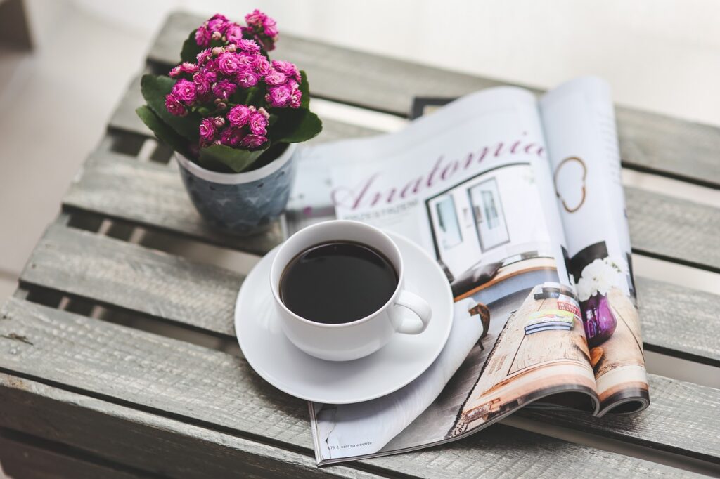 テーブル上のコーヒーと新聞と鉢植えの花